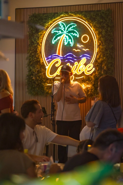 Cantante actuando frente al letrero de neón de Caribe 2.0